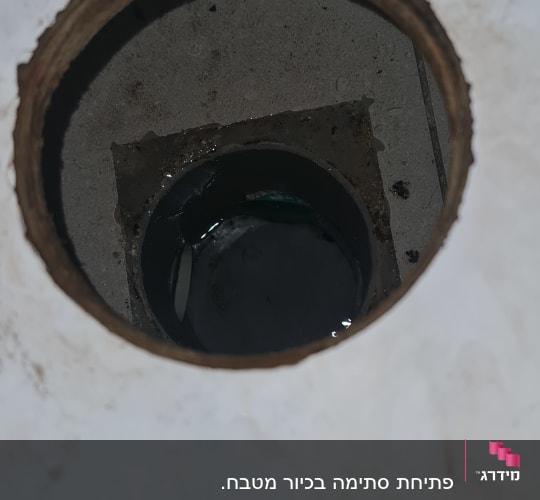 מבט לתוך פתח ניקוז וקופסת ביקורת ברצפה עם מים עומדים
